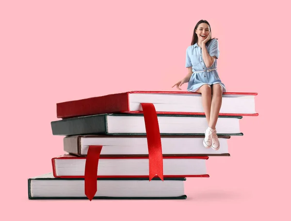Jovem Feliz Sentada Pilha Grandes Livros Contra Fundo Rosa — Fotografia de Stock