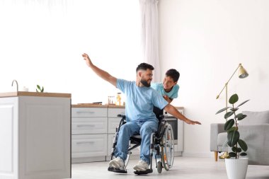 Küçük çocuk ve babası tekerlekli sandalyede eğleniyorlar.