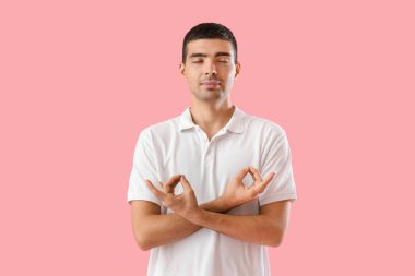 Young guy meditating on pink background