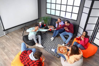 Evde lezzetli pizza ve kola içen bir grup arkadaş.