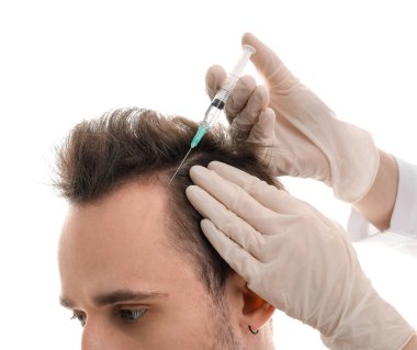 Genç adam beyaz arka planda saç büyümesi için iğne oluyor, yakın plan.