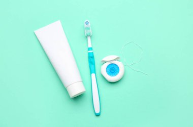 Turkuaz arka planda diş ipi, fırça ve tüp diş macunu
