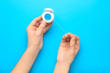 Mavi arka planda diş ipi tutan kadın.