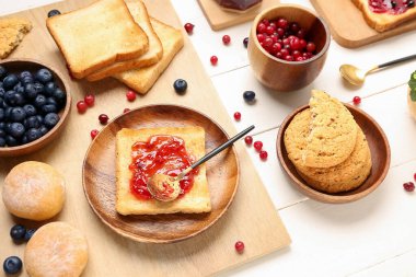 Hafif ahşap arka planda reçelli, böğürtlenli ve kurabiyeli lezzetli tostlar.