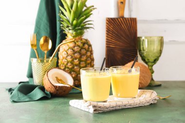 Lezzetli ananas kokteyli, pipet ve hindistan cevizi renkli masada.