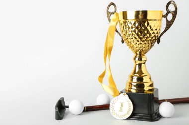 Birincilik madalyası, golf sopası ve hafif arka planda topları olan altın kupa.