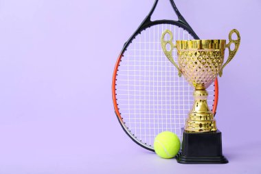 Altın bardakta tenis raketi ve eflatun kaplama top.