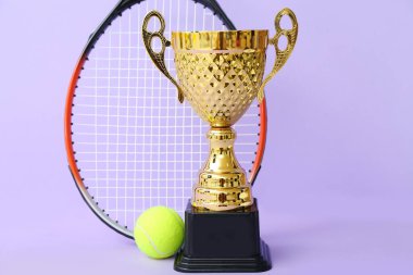 Altın bardakta tenis raketi ve eflatun kaplama top.