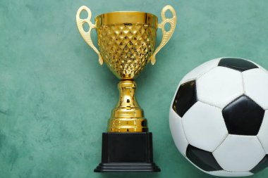 Yeşil arka planda futbol topu olan altın kupa