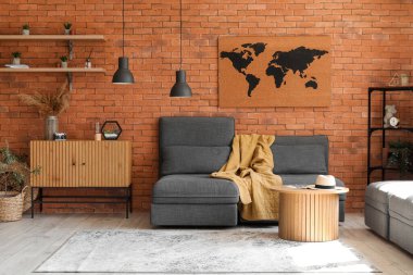 Tuğla duvarın yanında rahat koltukları ve sehpası olan şık bir oturma odası.