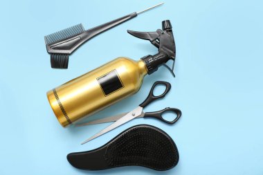 Mavi arka planda fırça ve makas ile saç spreyi