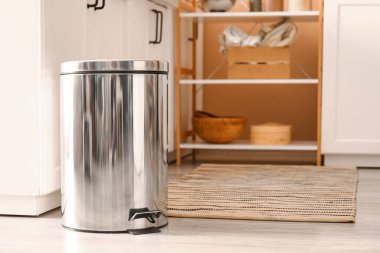 Modern mutfakta yerde metal çöp kutusu var.