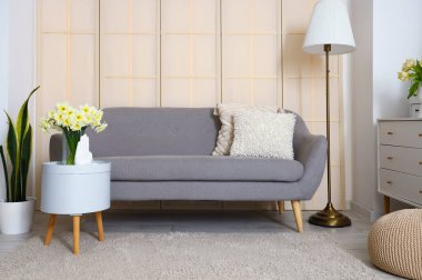 Gri kanepesi, masası ve lambası olan oturma odasının içinde.