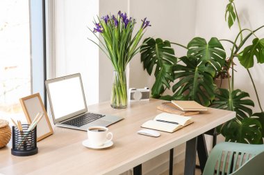Laptop, not defteri, kahve fincanı ve çiçekli modern işyeri