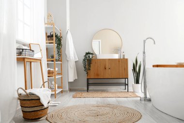 Banyonun içinde küvet, ahşap dolap ve ayna var.