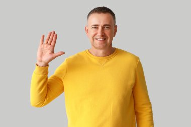 Olgun adam ışık arkaplanda elini gösteriyor