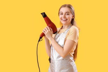 Sarı arka planda kurutma makinesi olan kadın kuaför.