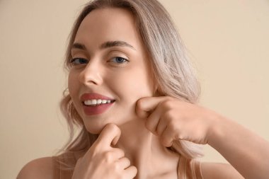 Bej arka plan üzerinde yüz geliştirme egzersizi yapan genç kadın, yakın plan.