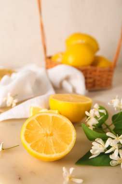 Beyaz masanın üzerinde çiçek açan dalları olan bir sepet limon.