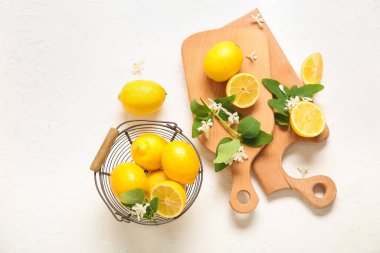 Beyaz masada çiçek açan dalları olan tahtalar ve limon sepeti.