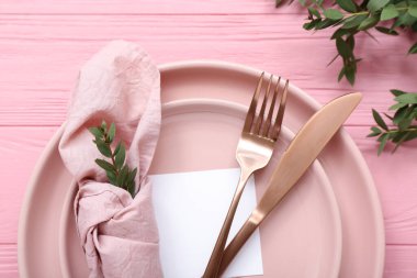 Boş kartlı şık masa ayarları ve pembe ahşap arka planda dallar.