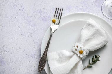 Katlanmış peçeteli tabaklar, gümüş çatal bıçak takımı ve grunge beyaz arka planda cam.