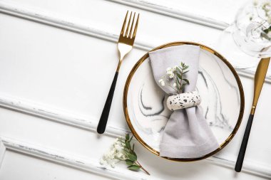 Katlanmış peçete, altın çatal bıçak ve ahşap beyaz arka planda cam.