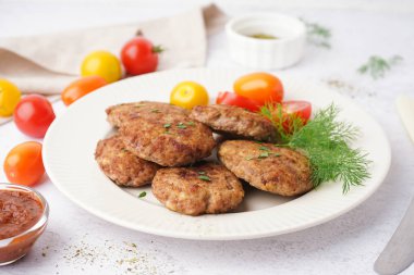 Mutfaktaki beyaz grunge masasında pirzola, dereotu ve domates tabağı.