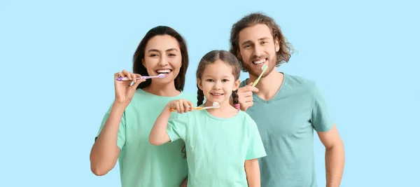 Happy family brushing teeth on light blue background