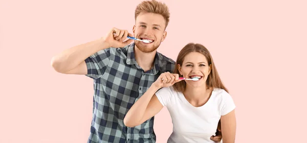粉红背景的快乐夫妻刷牙 — 图库照片