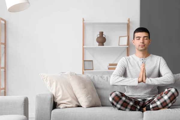 Young Man Pajamas Meditating Sofa Home — Foto de Stock