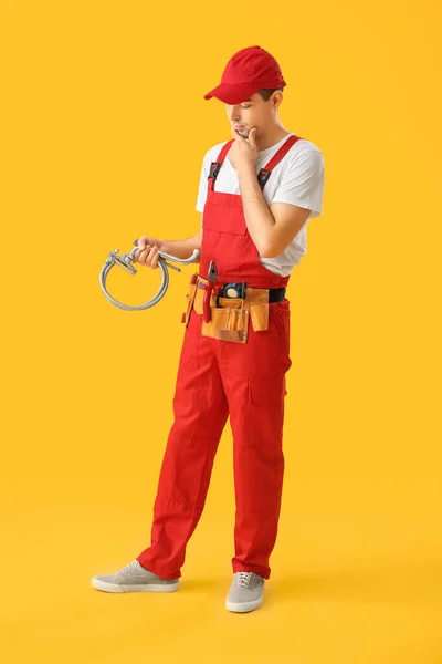 Thoughtful Young Plumber Flexible Hose Yellow Background — Stock Photo, Image