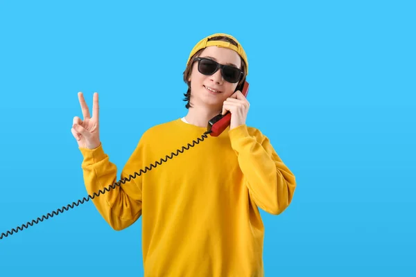 Cooler Teenager Mit Handy Hörer Zeigt Siegesgeste Auf Blauem Hintergrund — Stockfoto