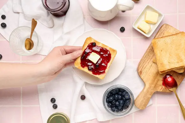 Elinde lezzetli tost ve pembe fayanslı yaban mersini reçeli tutan kadın.