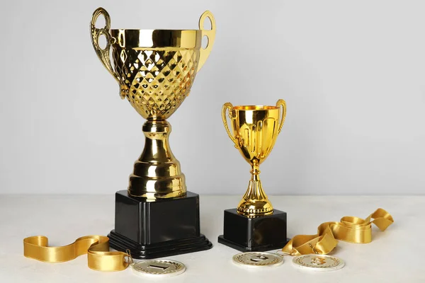 Copos Ouro Com Medalhas Prêmio Mesa Perto Parede Cinza — Fotografia de Stock