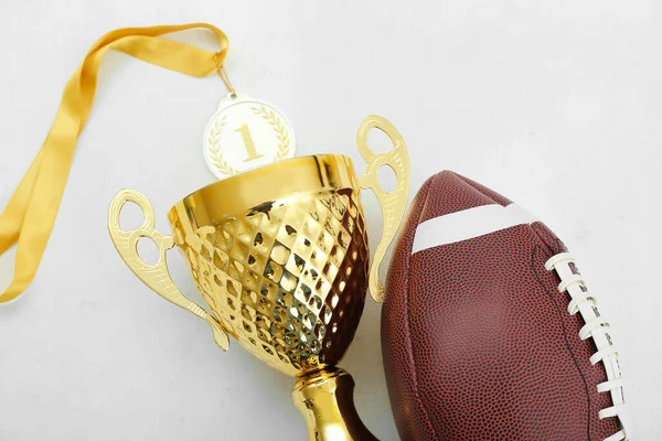 stock image Gold cup with first place medal and rugby ball on white background, closeup