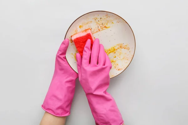 グレーの背景にスポンジで汚れたプレートを洗うゴム手袋の女性の手 — ストック写真
