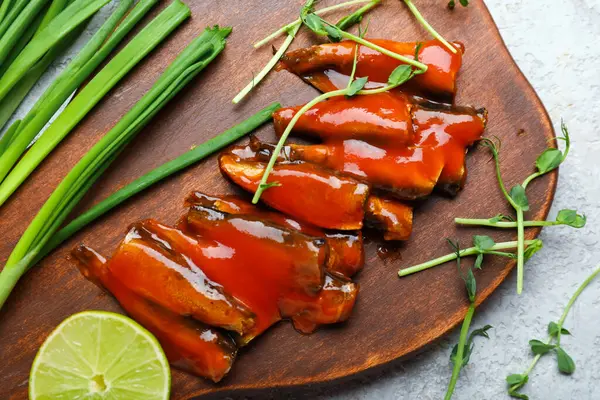 stock image Board with canned fish in tomato sauce, lime, scallions and microgreens on grey table