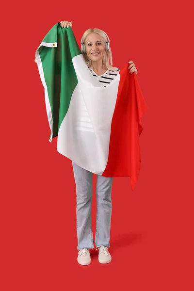 Dojrzała Kobieta Słuchawkach Flagą Włoch Czerwonym Tle — Zdjęcie stockowe