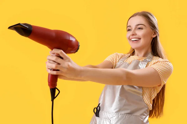 黄色の背景に乾燥機と女性の美容師 — ストック写真
