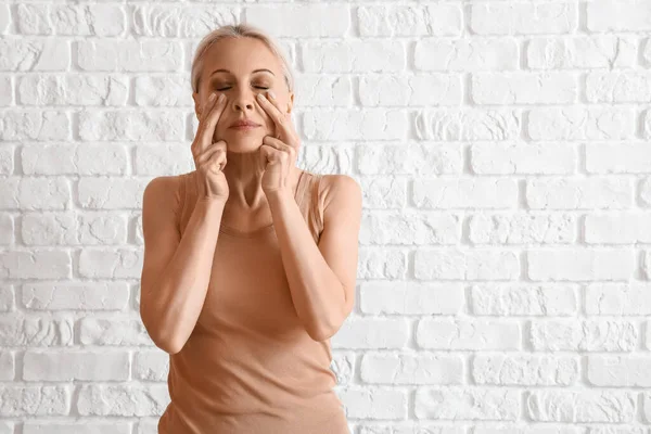 Mature Woman Doing Face Building Exercise White Brick Background — Stock Photo, Image