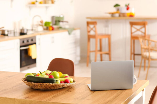 Healthy vegetables with laptop on table in kitchen