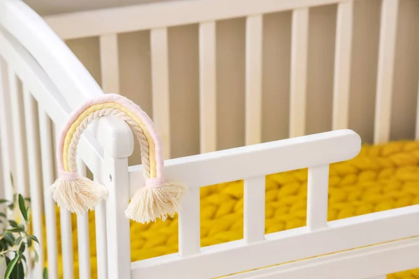 Baby crib with toy in light bedroom, closeup