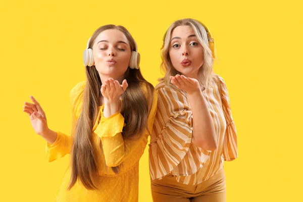 Young Sisters Headphones Blowing Kisses Yellow Background — Stock Photo, Image