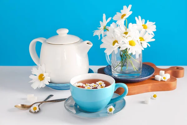 木地板 一杯天然洋甘菊茶 蓝墙旁边的白桌上的花朵 — 图库照片