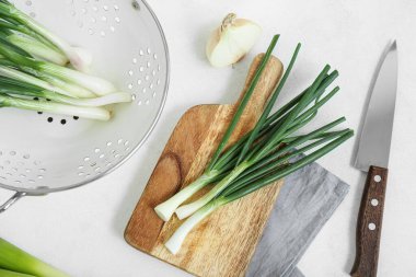 Açık arkaplanda yeşil soğanlı kolander ve pansiyon