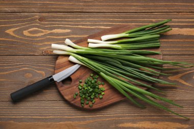 Ahşap zemin üzerinde taze taze soğan dilimleri olan tahta.