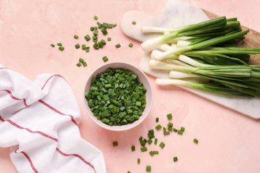 Pembe arka planda taze yeşil soğanlı bir kase dilimler ve yiyecek.