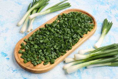 Mavi zemin üzerinde taze taze soğan dilimleri olan tahta