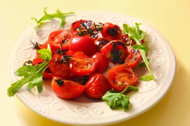 Lezzetli ızgara domates ve sarı arka planda roka.